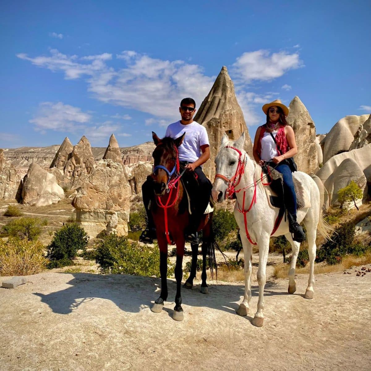 A couple on a bay and a grey horse posed among fairy chimneys